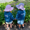 Two children wearing the Childs's Denim Jacket, both with name monograms on the back