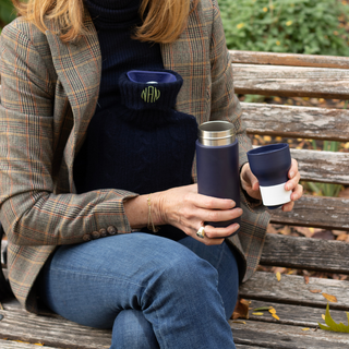 Person sitting on an embroidered personalised hot water bottle cover. 