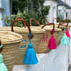 Handmade Yarn Tassels on Monogrammed Baskets Lined Up on a Wall Outside - Initially London