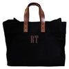 A black cotton canvas tote bag, with leather handles and a large monogram