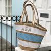 100% Jute, Blue, White and Natural stripe bag outside a house door. Large, Three Letter monogram in the top white stripe 