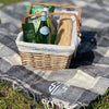100% British wool with a nylon, water-resistant backing Picnic Rug in Grey Check, laid out with picnic items in a basket on top. 
