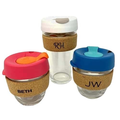 Three glass keep cups, with  Multi-coloured lids, with a cork holder. Each cork holder has an etched monogram