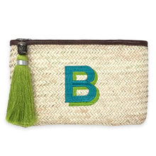 A clutch made from Hand woven from Palm Leaf in Morocco and and features a leather trim and an inside pocket. Monogramed with a large shadow font letter