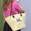 Palm leaf with leather handles Market Basket with a two letter monogram. The straps go over the shoulder as shown here.