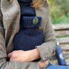 A women holding onto the navy cashmere hot water bottle, in an outdoor setting