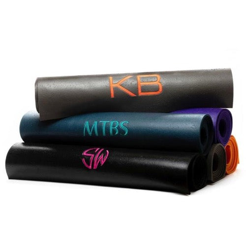 A collection of monogrammed Om Yoga Mats, made from phthalate-free PVC with no toxins. Each has a large monogram in various colours - Initially London