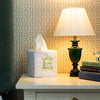 100% linen Tissue Box Cover with a large embroidered monogram on the front. It's in a home setting, next to a pile of books and lamp